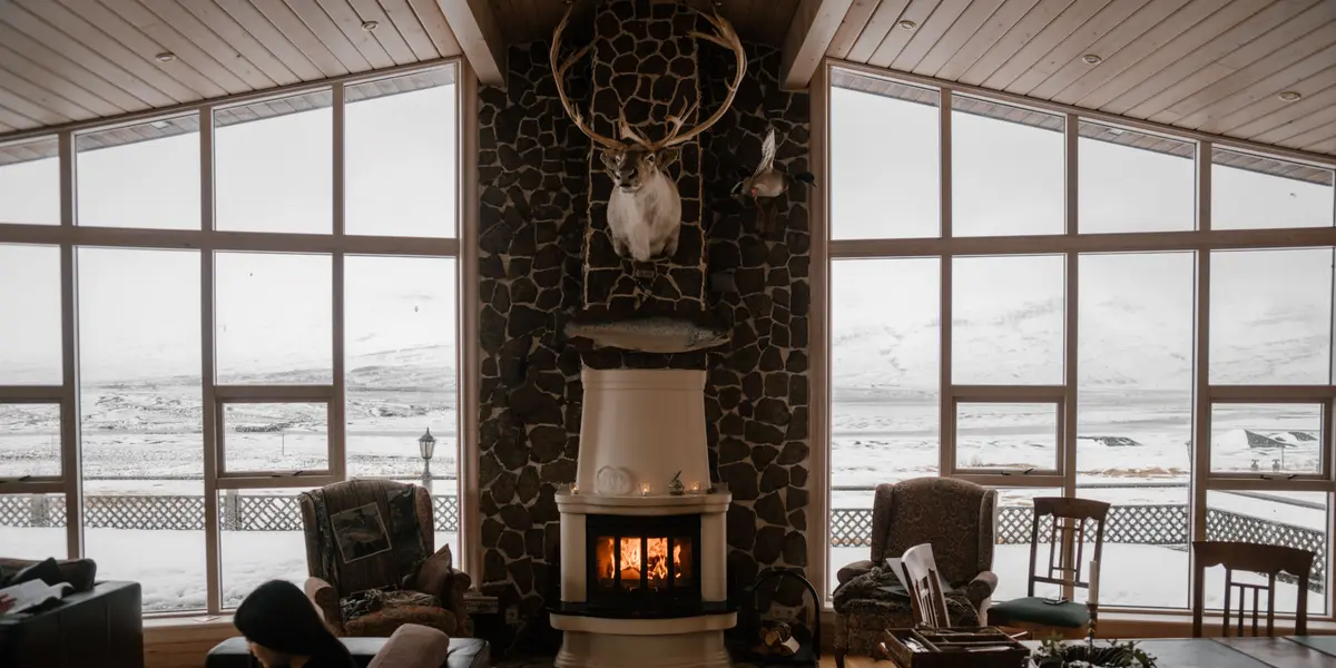 Salon avec poêle à bois devant de grandes baies vitrées en hiver