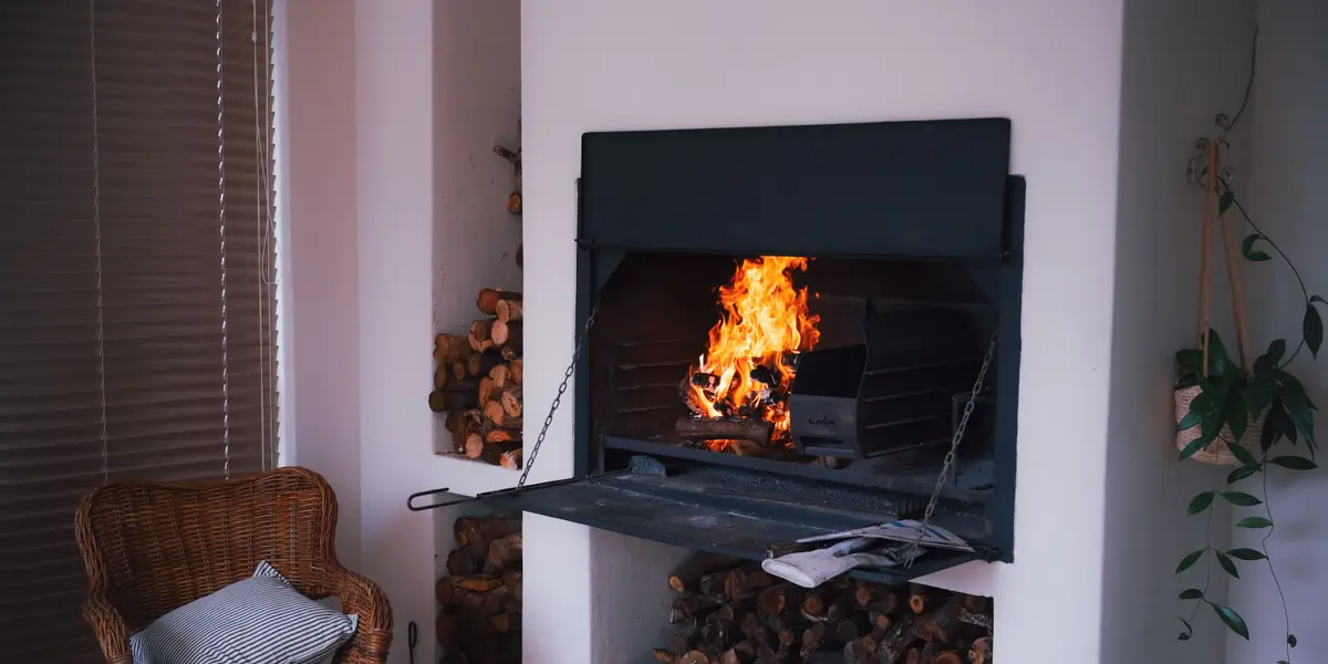 Foyer encastré avec réserve de bois et fauteuil en osier