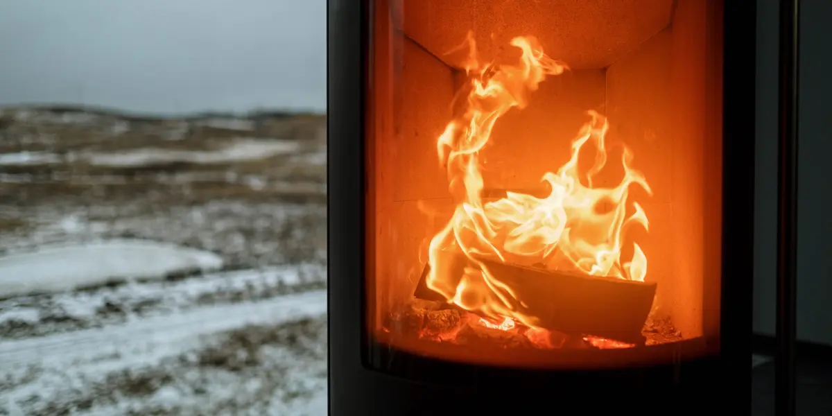 Poêle moderne à flamme visible, paysage enneigé derrière la fenêtre